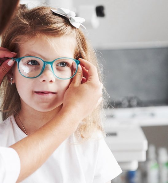 New look. Doctor giving the child new glasses for her vision.